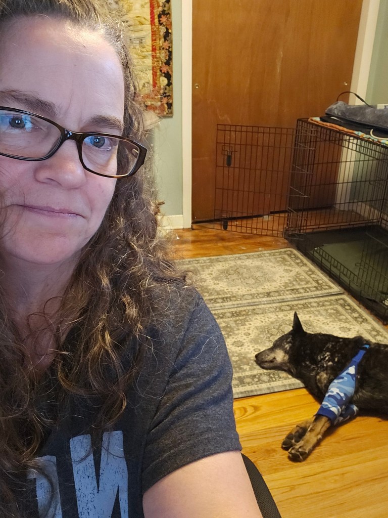 Me sitting at my computer with Ringo asleep on the floor behind me